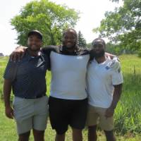 Three football alums standing on the golf course.